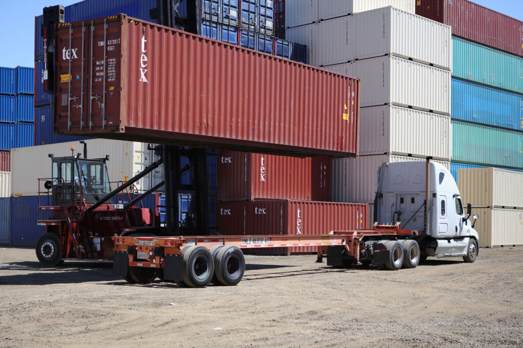Loading a cargo-worthy shipping container onto a chassis for delivery.